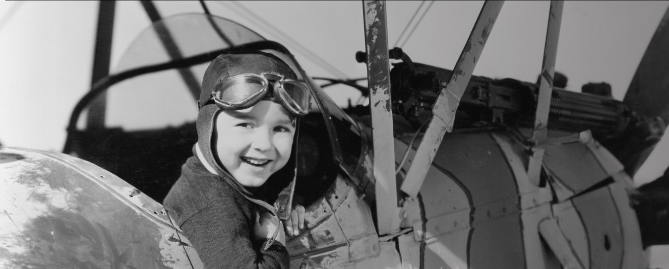 A child smiling whilst sitting in an biplane